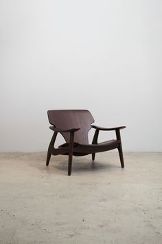 a brown chair sitting on top of a cement floor next to a white wall in an empty room