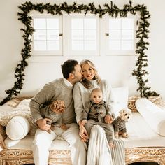 a man and woman are sitting on a couch with their two children in front of them