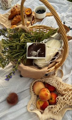 a basket filled with fruit and cheese on top of a white cloth covered tablecloth