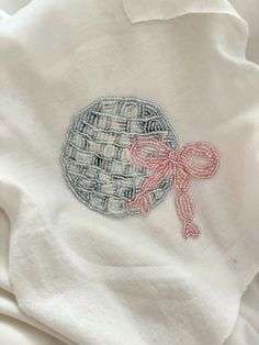 a white t - shirt with a pink bow on the front and an embroidered design on the back