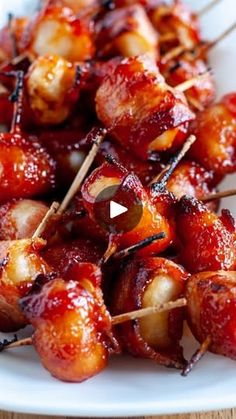 the skewers are covered with bacon and other toppings on a white plate