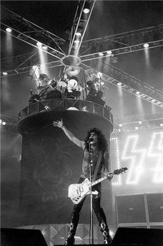 the band kiss performing on stage in front of a large sign that reads kiss live