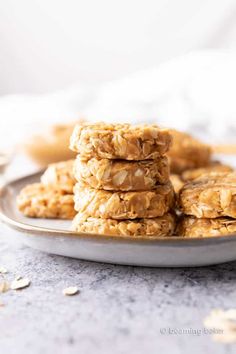 oatmeal cookies stacked on top of each other in a metal plate with scattered oats