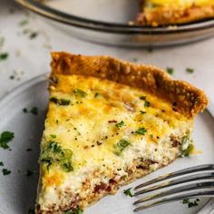 a slice of quiche on a plate with a fork next to the rest of the pie