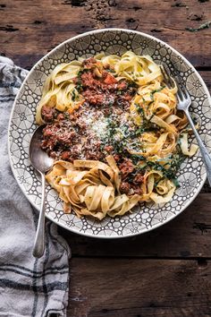 a bowl filled with pasta and meat sauce on top of a table next to a fork