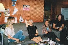 three women sitting on a couch in a living room with papers flying from the ceiling