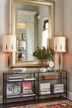 a living room with a large mirror on the wall and a book shelf in front of it