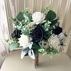 a bridal bouquet with white and black flowers on a chair in front of a wall