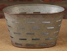 a large metal basket sitting on top of a brown cloth covered floor next to a brick wall