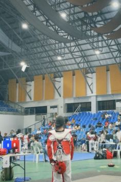 a man standing in the middle of a gym holding a red and white frisbee