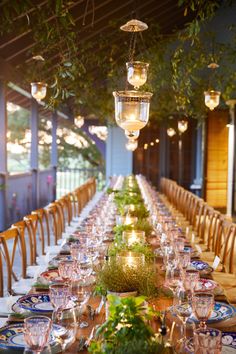 a long table is set with plates and glasses for an outdoor dinner or party event