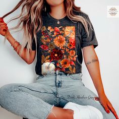 Unveil the beauty of autumn with our 100% Organic Boho Fall Cottagecore Shirt. This tee is delicately adorned with painted earthy flowers, pumpkins, apples, berries, and acorns, bringing the warm and cozy vibes of fall to life. Made from 100% organic ring-spun cotton, this shirt offers comfort while being gentle on the planet. Its eco-friendly design makes it a perfect pick for those who cherish sustainable fashion and love to stay connected with nature. Whether you're enjoying a peaceful walk t Artistic Floral Print Tops For Spring, Fall Floral Print Relaxed Fit Shirt, Floral Print Relaxed Fit Shirt For Fall, Short Sleeve Floral Print Tops For Fall, Multicolor Floral Print T-shirt For Fall, Fall Cotton T-shirt With Floral Print, Fall Short Sleeve Shirt With Plants Print, Casual Fall Floral Tops, Fall Floral Print T-shirt