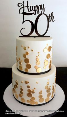 a white cake with gold confetti on it and the words happy 50th written in black