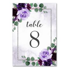 a table number with purple flowers and greenery