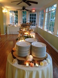 a table with plates and candles on it in a room that has many windows,