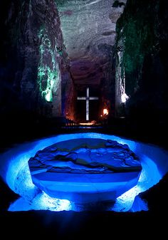 a cross is lit up in the middle of a cave