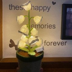 a crocheted plant with white flowers in a pot next to a sign that says, these happy memories forever