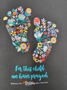 two embroidered gloves with flowers and words written on the front, one saying for this child we have passed