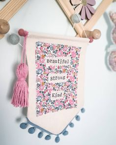 a pink banner hanging from the side of a wall with flowers and words on it