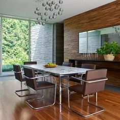 a dining room table with chairs and a bowl of fruit on top of the table