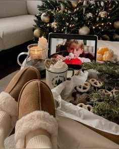 a person's feet in front of a christmas tree with cookies and coffee mugs