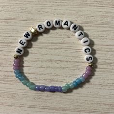 a white beaded bracelet with the words new romantics written on it