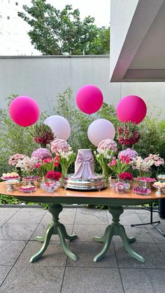 a table topped with lots of pink and white balloons