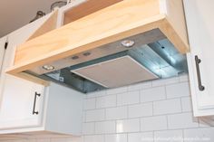 a kitchen with white cabinets and an overhead range hood