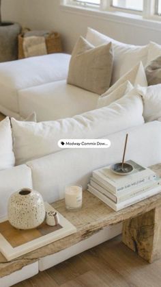 a white couch sitting next to a wooden table with books on it and a candle