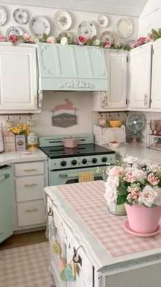 a pink and white kitchen with lots of plates on the wall above the stove top