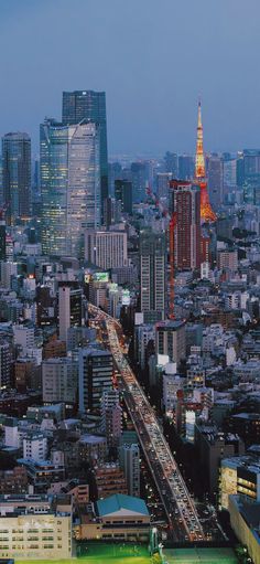 an aerial view of a city at night with traffic on the road and tall buildings in the background