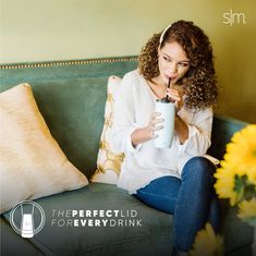 a woman sitting on a couch drinking from a cup