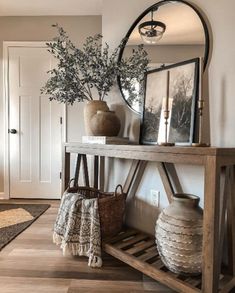 a wooden table with vases and pictures on it in front of a mirror over a shelf