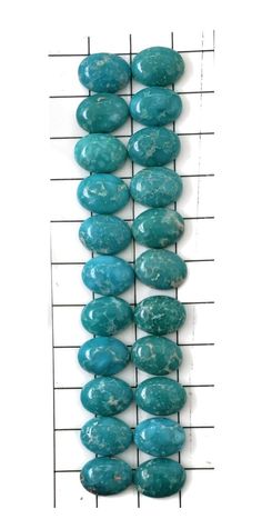 several turquoise stones are arranged on a wire rack in front of a white wall with lines