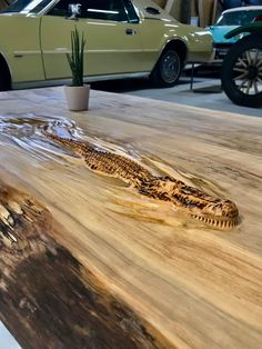 a close up of a wooden table with a plant on it and cars in the background