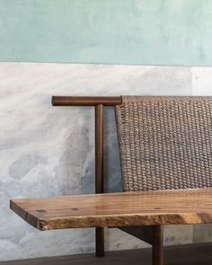 a wooden bench sitting in front of a wall next to a basket on top of it