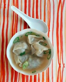 a white bowl filled with dumplings on top of a striped table cloth next to a spoon