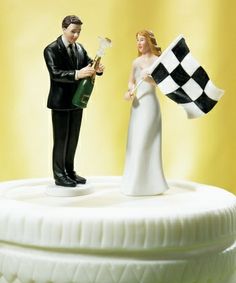 a wedding cake topper with a bride and groom holding a checkerboard flag