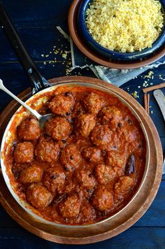 meatballs and rice in a bowl on a blue tablecloth with utensils