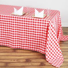 a red and white checkered tablecloth with two paper boats on it, ready to be served