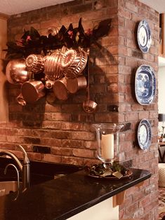 a brick wall with pots and pans hanging on it's side next to a counter