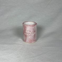 a small pink cup with writing on it