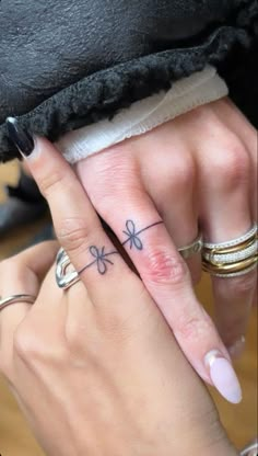 two people with matching rings on their fingers, one has a clover tattoo on the middle finger