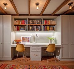 two yellow chairs sitting in front of a desk with bookshelves on top of it