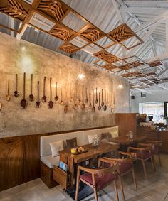 a restaurant with wooden tables and chairs, hanging utensils on the wall above them