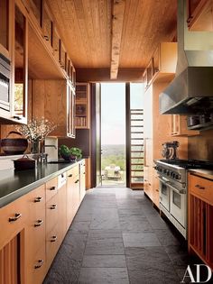 a kitchen with wooden cabinets and black counter tops next to an open door that leads to a balcony