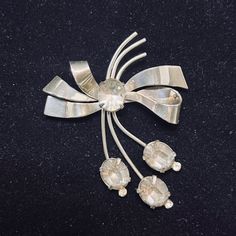 "Elegant vintage Coro brooch featuring a bow design adorned with clear glass rhinestones. Made from sterling silver, this piece is a testament to Coro's quality craftsmanship and timeless style. * Vintage Coro brooch * Features a bow design * Adorned with clear glass rhinestones * Made from sterling silver * Testifies to Coro's quality craftsmanship and timeless style It measures:  2\" wide X 2 5/8\" tall It comes with a gift box. (Jewelry #5190) USA Seller!! Estate sale find.   We do not Clean or Polish our Estate Jewelry to preserve the authentic patina we will leave that to you.  We also have Jewelry, Hallmark Ornaments, Dept 56, Vintage Glassware and many other items.  We will combine shipping for multiple items if possible. Features: * Working Clasp Size: Womens 2\" wide X 2 5/8\" tal Retro Silver Brooches For Anniversary, Silver Retro Brooches For Anniversary, Retro Silver Brooches For Formal Occasions, Silver Retro Brooches For Formal Occasions, Wedding Brooches, Gift Box Jewelry, Bow Brooch, Wedding Brooch, Rhinestone Bow