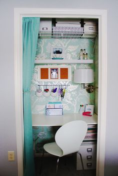 a white chair sitting in front of a desk under a blue curtain with pictures on it