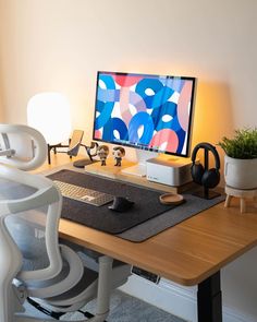 a desk with a computer and headphones sitting on it's side, next to a potted plant