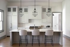 a kitchen with white cabinets and bar stools